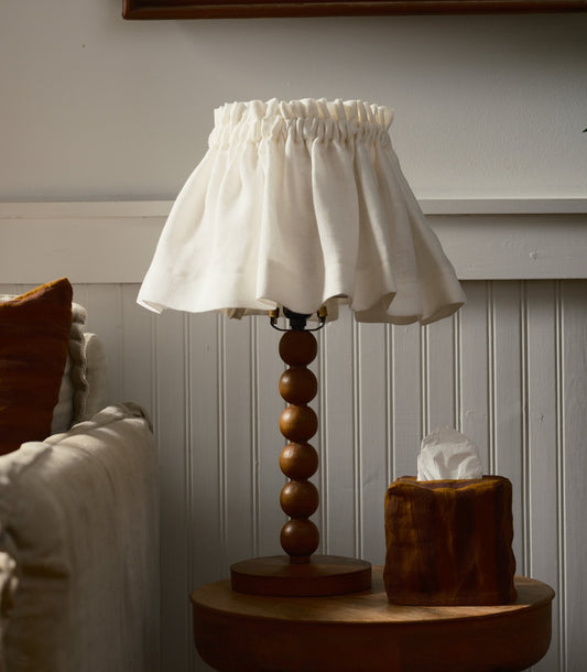 Lamp with a wooden base and white shade on a table.