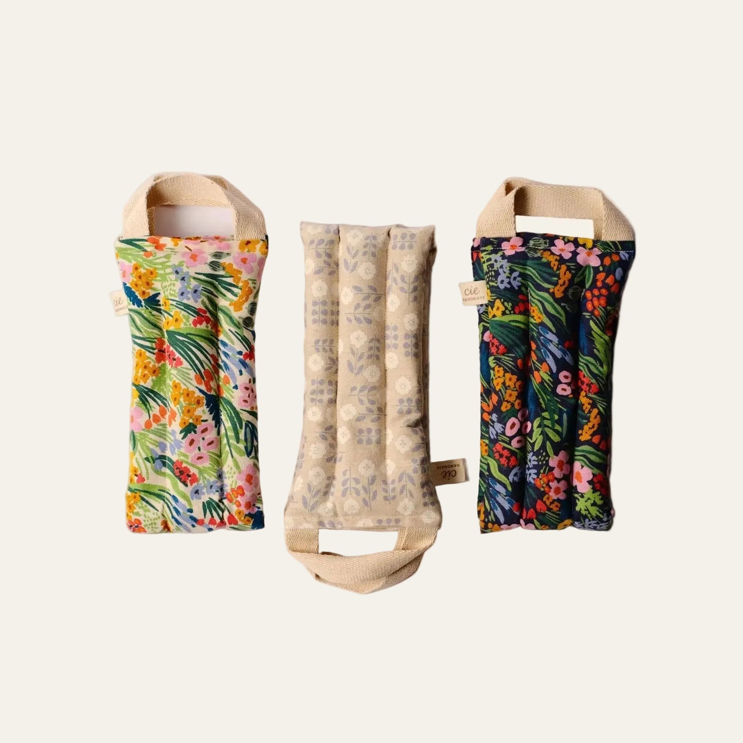 Three fabric neck wraps with floral patterns on a beige background