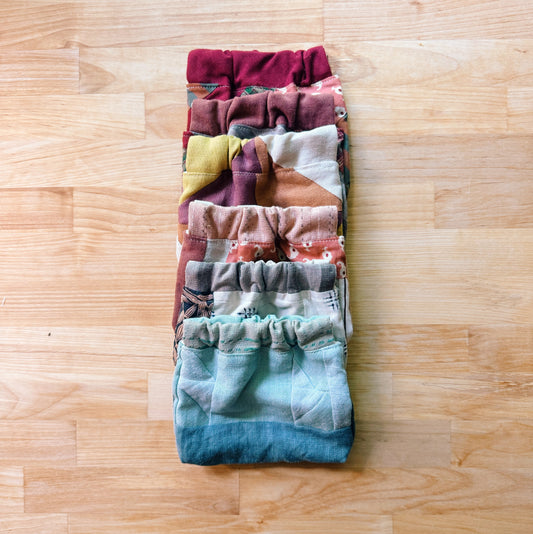 Stack of folded colorful pouches on a wooden surface
