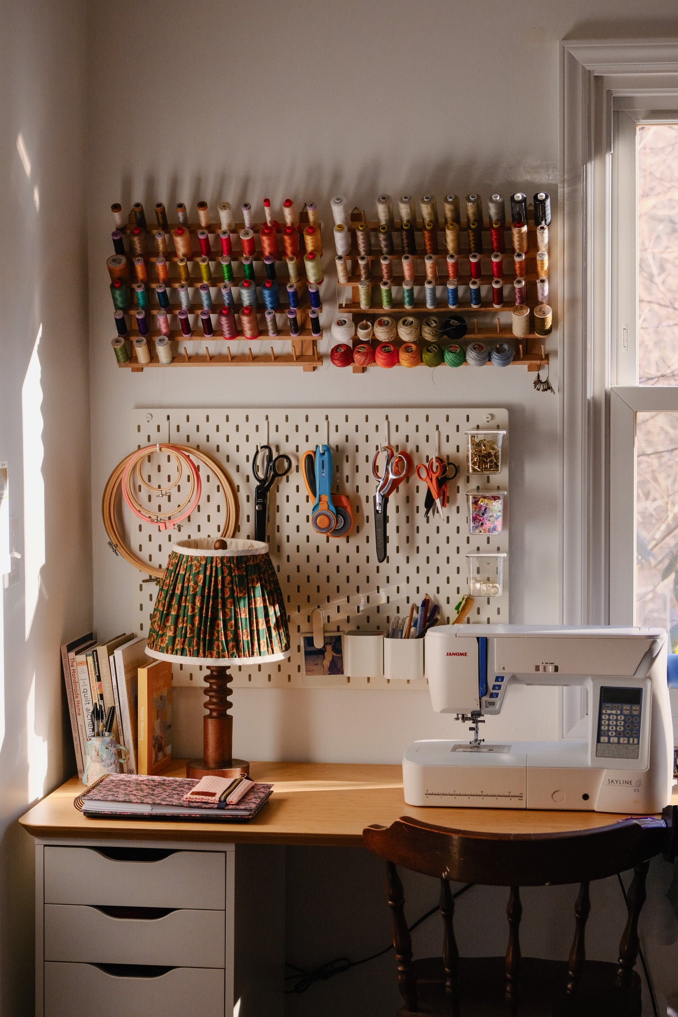 Sewing room with sewing machine, thread spools, and pegboard