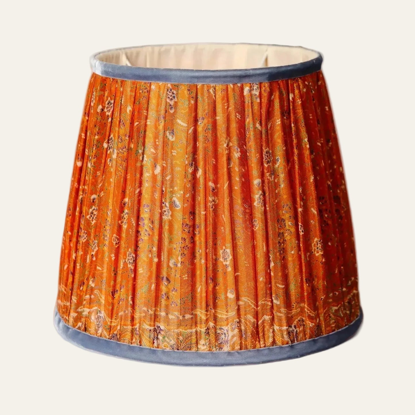 Decorative lampshade with orange floral pattern and blue velvet trip on a beige background