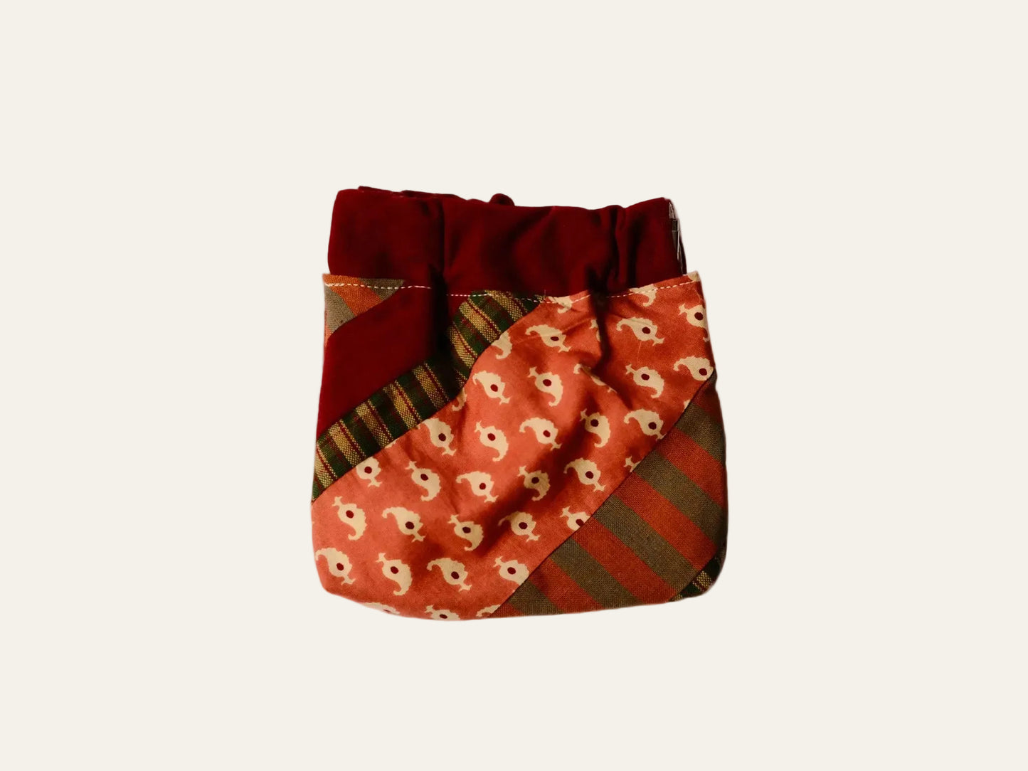 Patchwork pouch with red and brown patterns on a beige background