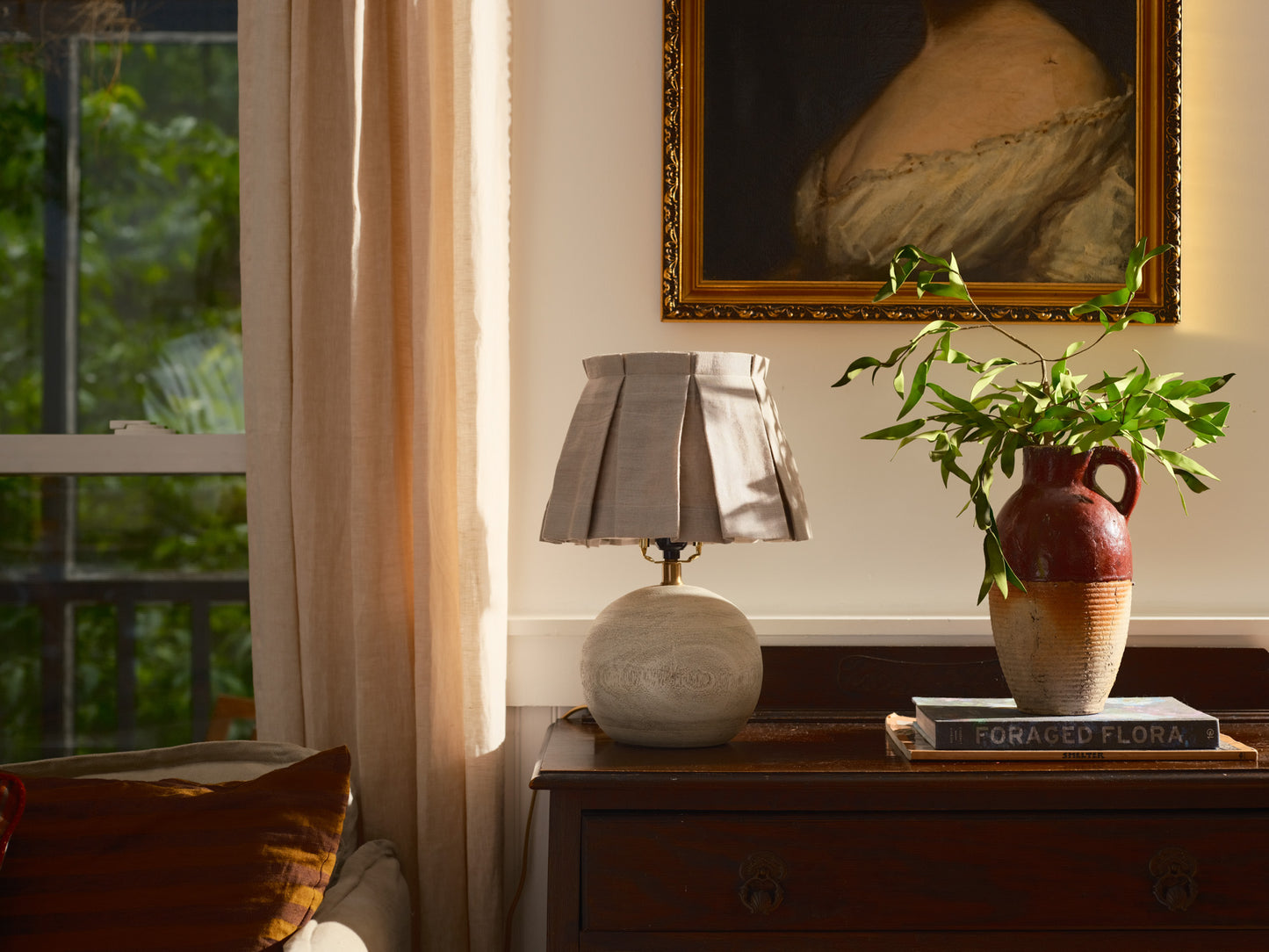 Lamp on a wooden surface with a plant and books in the background