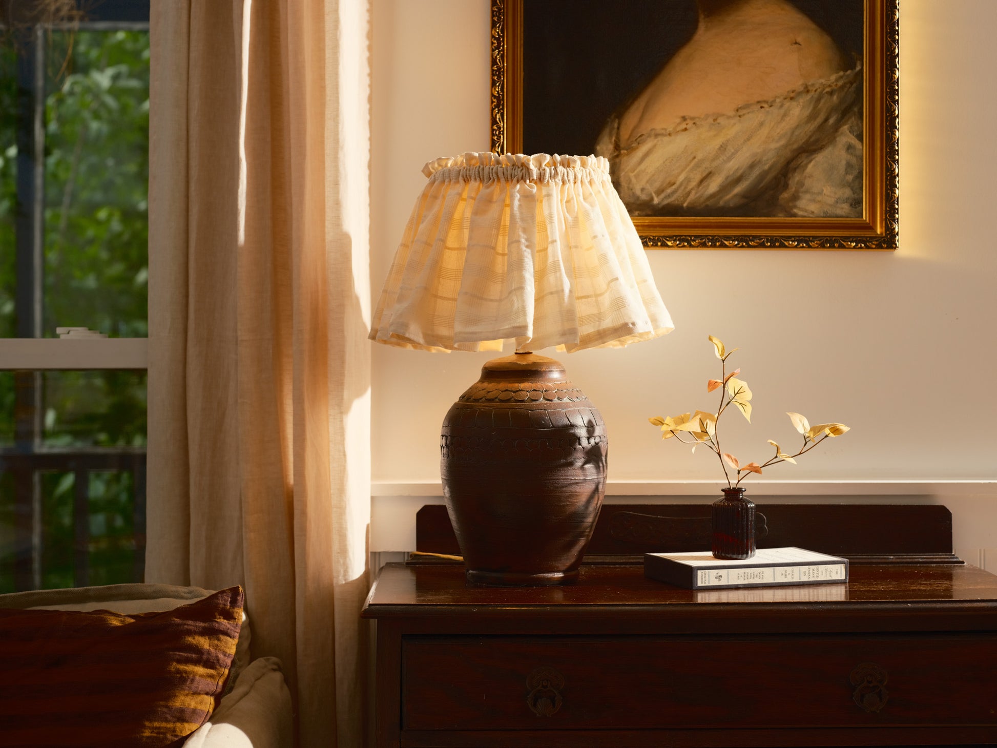Lamp on a wooden table with a painting in the background