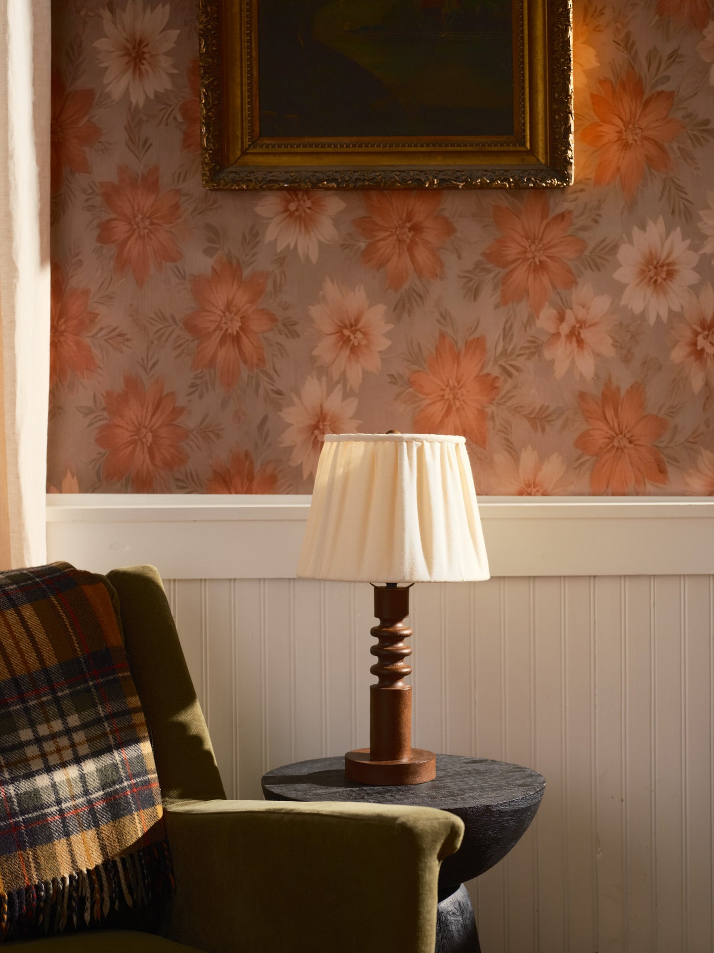 Nostalgic interior with floral wallpaper, green armchair, and wooden lamp.