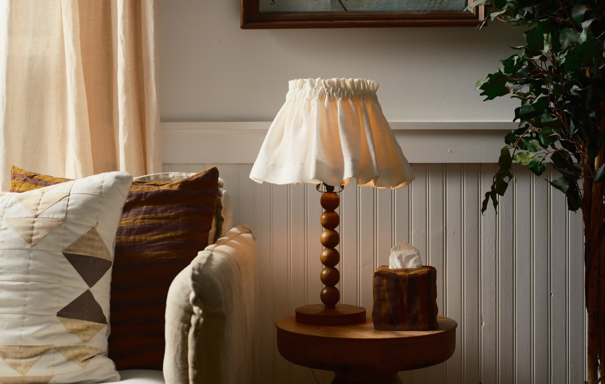 Lamp on a side table next to a sofa with cushions in a cozy living room setting.