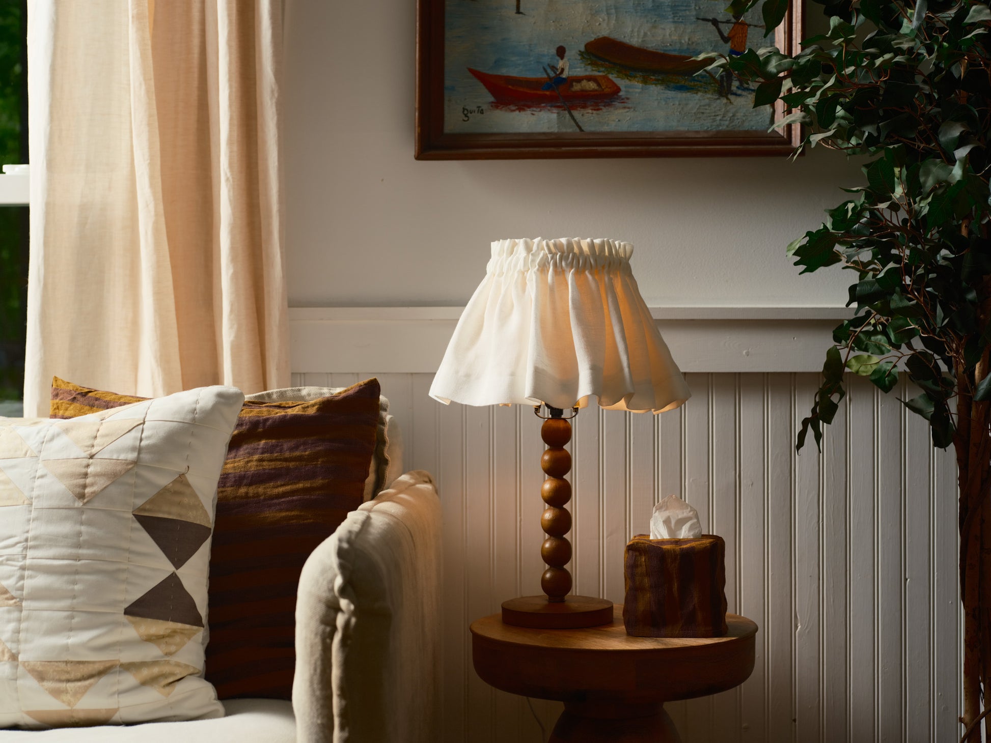 Lamp on a side table next to a sofa with cushions in a cozy living room setting.